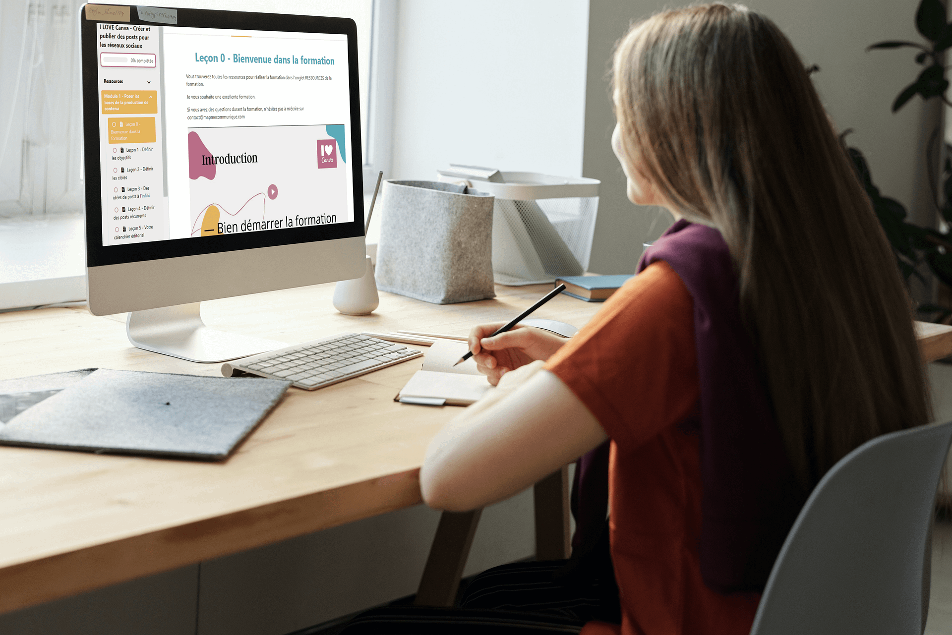 iMac on the wooden desk with a girl taking notes_image